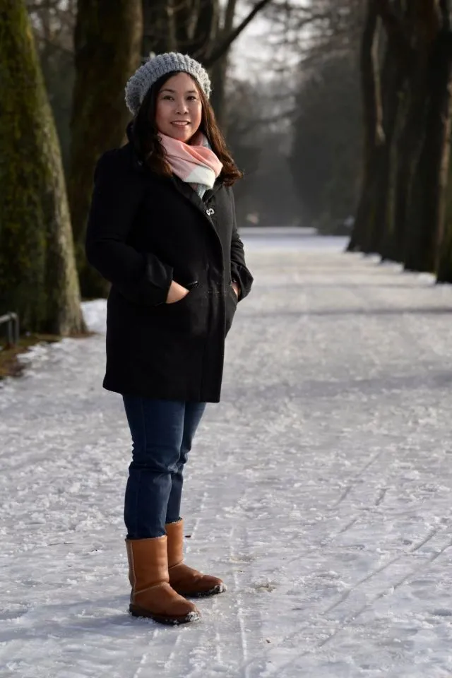 Woman posing amongst trees. Floor is covered in snow.