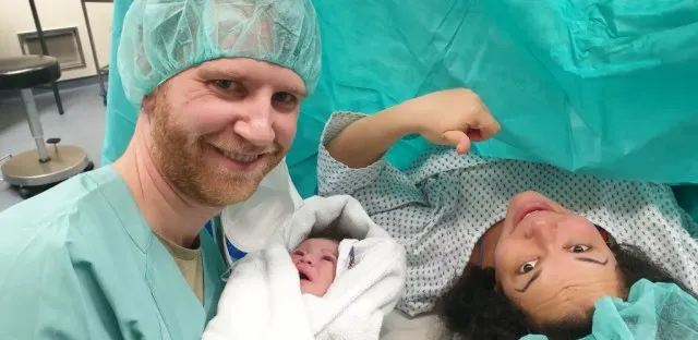 Man, woman and newborn child posing after c-section procedure.